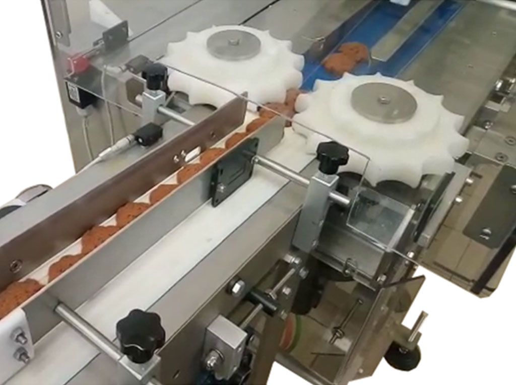 Dettaglio di allineatore automatico per biscotti con ruote a stella in plastica bianca per il distanziamento dei prodotti.