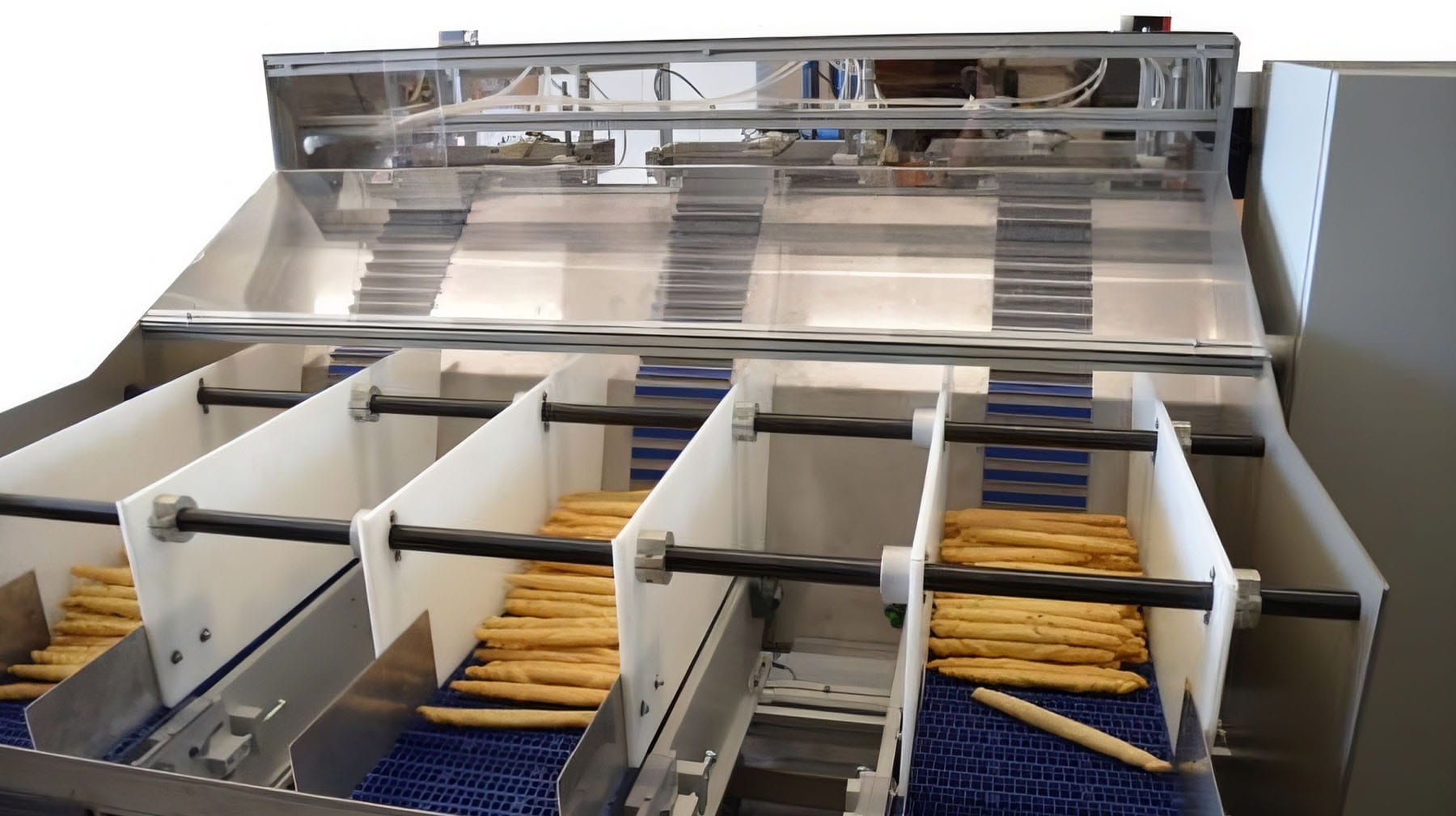 Grissini disposti su canali di carico con tappeti blu a nido d'ape all'interno di un macchinario di distribuzione automatica.
